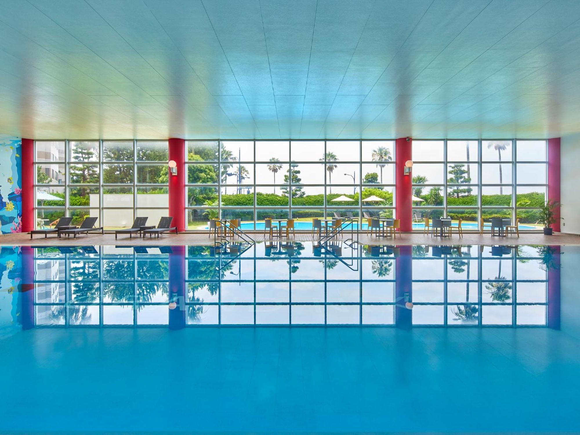 מלון Urayasu Grand Nikko Tokyo Bay Maihama מראה חיצוני תמונה The photo shows an indoor swimming pool with bright blue water. The pool area is spacious, characterized by large windows that allow natural light to flood in, creating a vibrant atmosphere. The walls are painted in a soft color, with accents of red.